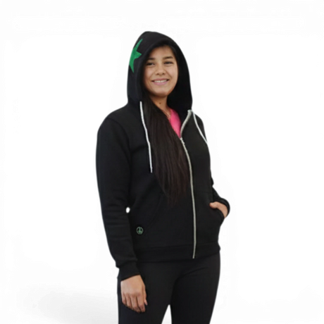 Pivotstar black cotton blend zip-up hoodie with green star appliqué on hood and white drawstrings. Model wears pink shirt and black capri pants.